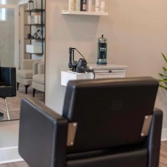 A black styling chair at a station in the salon