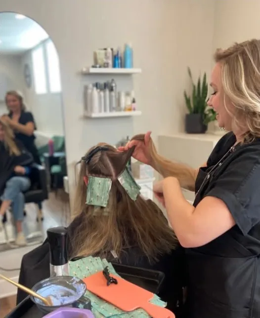 A stylist placing foils in a client’s hair